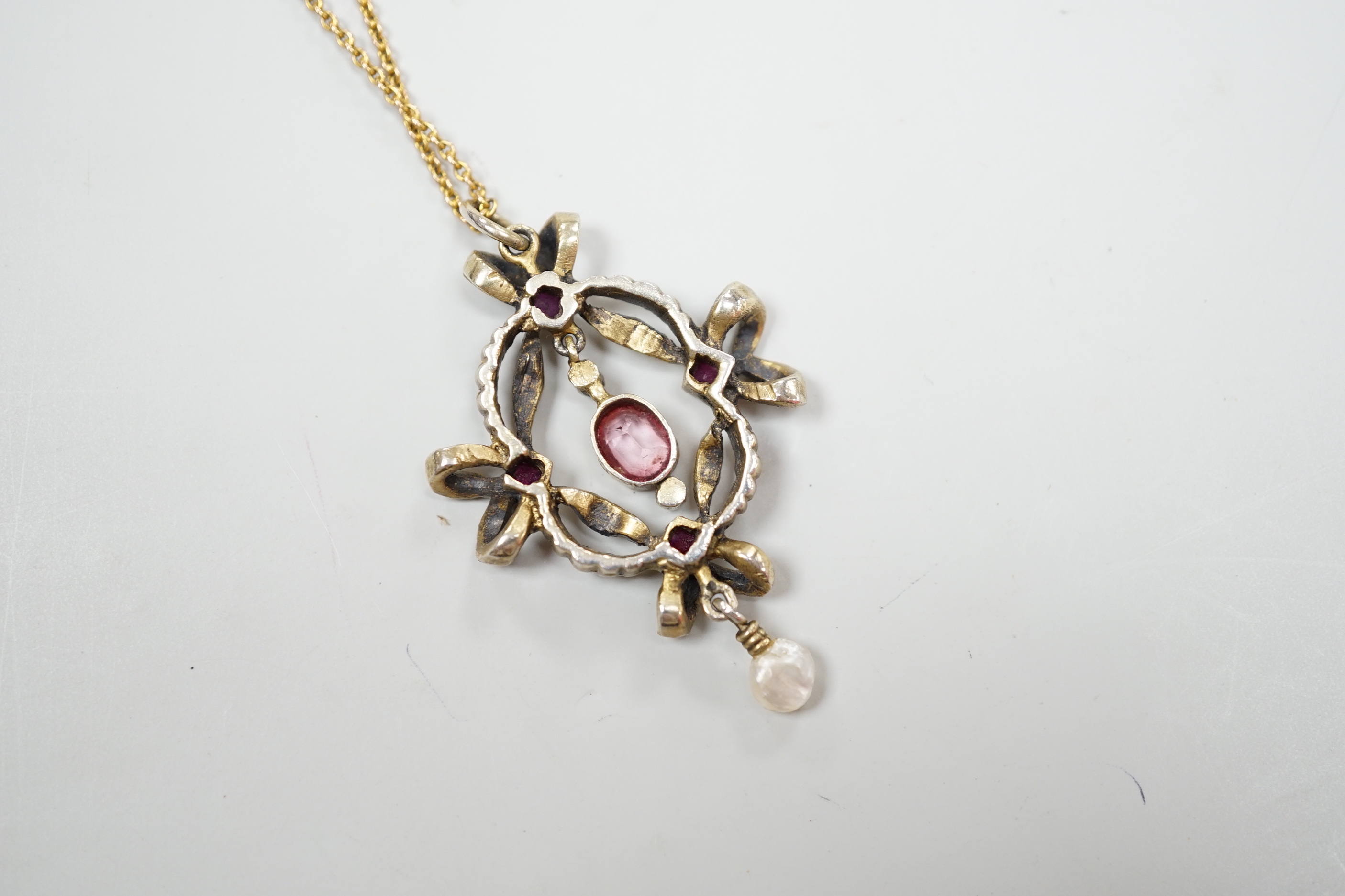 An early 20th century Continental gilt white metal pendant set with rubies, seed pearls and other gems, on a fine gold chain, leather cased, pendant 4.5cm